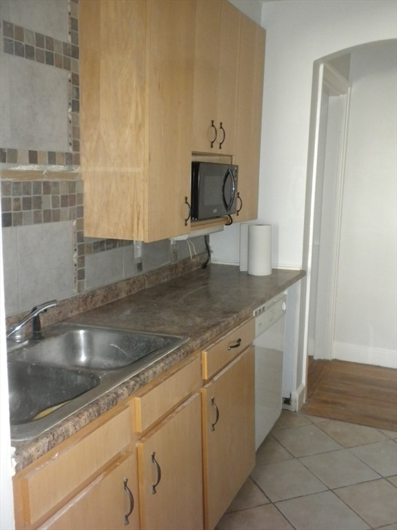 kitchen featuring dishwasher, light tile patterned floors, sink, and light brown cabinetry