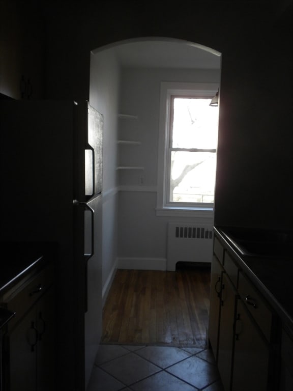 kitchen with radiator heating unit, white fridge, and hardwood / wood-style floors