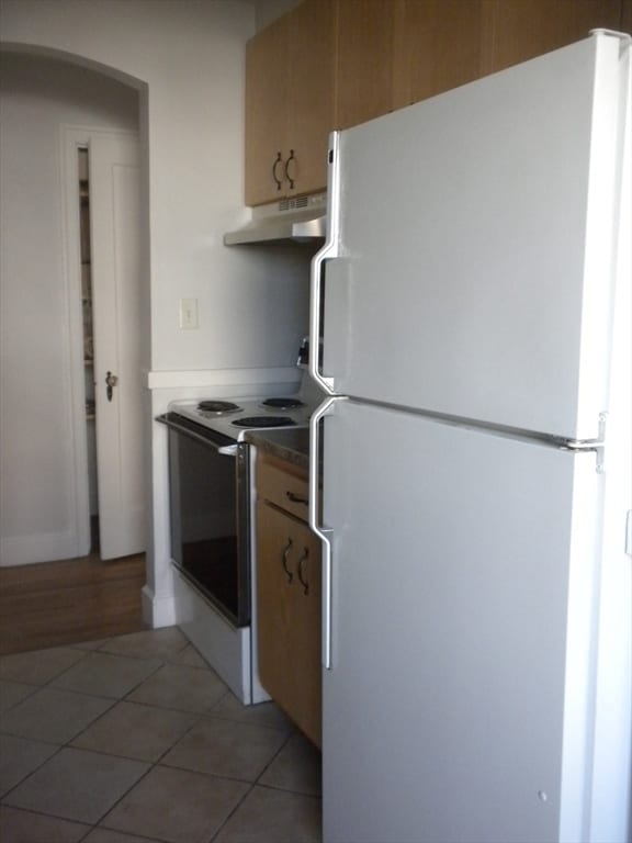 kitchen featuring electric range, white refrigerator, and tile patterned floors