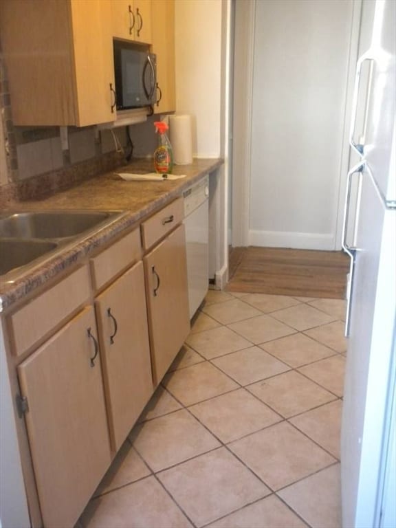 kitchen with white appliances, sink, light brown cabinetry, and light hardwood / wood-style flooring