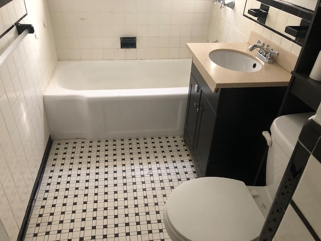 bathroom featuring vanity, toilet, tile walls, tasteful backsplash, and a tub