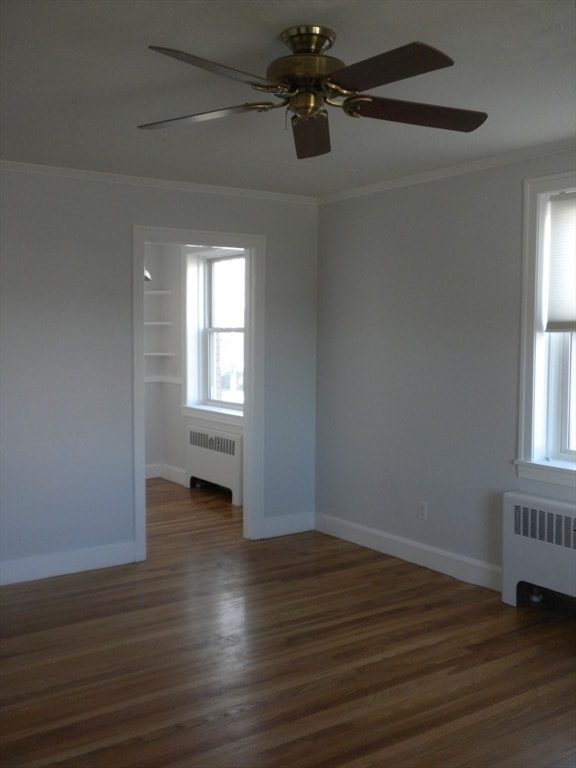 unfurnished room with radiator heating unit, crown molding, ceiling fan, and dark wood-type flooring