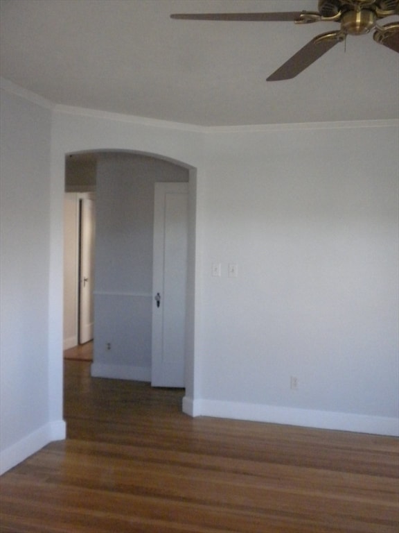 empty room featuring dark hardwood / wood-style floors, ceiling fan, and ornamental molding