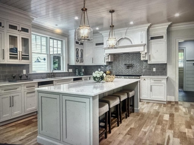 45 Widow Rites Ln, Sudbury, MA 01776 - kitchen with ornamental molding, a center island, a kitchen breakfast bar, decorative backsplash, and glass insert cabinets
