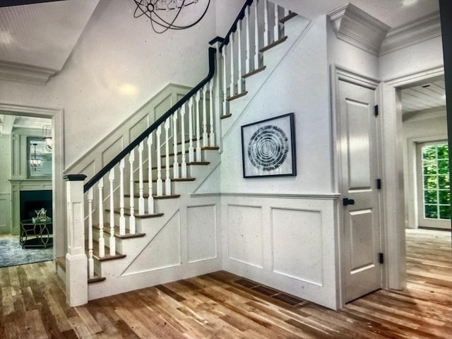 45 Widow Rites Ln, Sudbury, MA 01776 - stairs featuring wood finished floors, a decorative wall, a fireplace, crown molding, and wainscoting