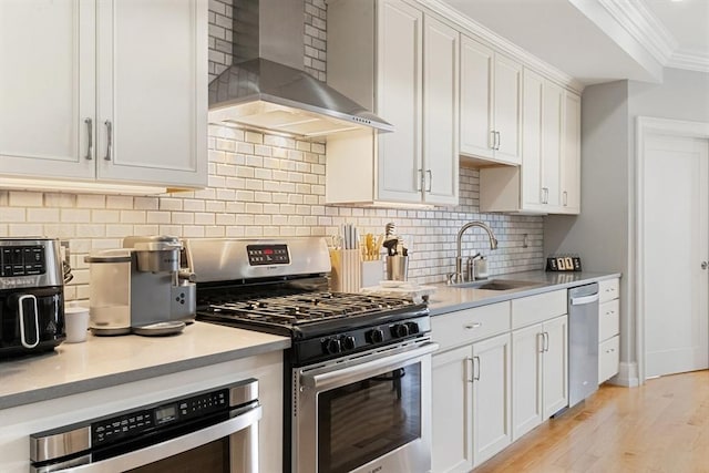 37 P St Unit 2, Boston, MA 02127 - kitchen with appliances with stainless steel finishes, wall chimney range hood, ornamental molding, white cabinets, and light wood-style floors