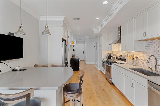 37 P St Unit 2, Boston, MA 02127 - kitchen featuring appliances with stainless steel finishes, a kitchen bar, wall chimney range hood, white cabinetry, and recessed lighting