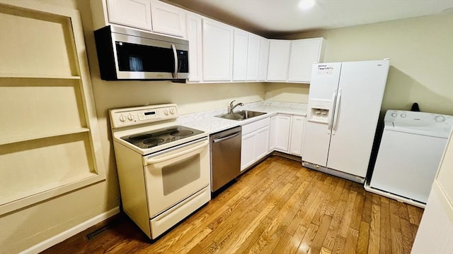 67 Amherst Rd Unit 67, South Hadley, MA 01075 - kitchen with stainless steel appliances, washer / dryer, white cabinetry, light countertops, and wood finished floors