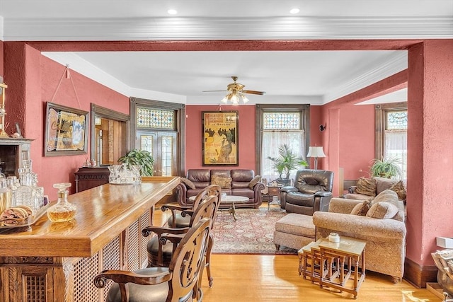 living room featuring ceiling fan, ornamental molding, and light wood-type flooring