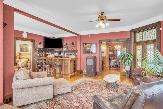 living room featuring crown molding, ceiling fan, bar, and light hardwood / wood-style flooring