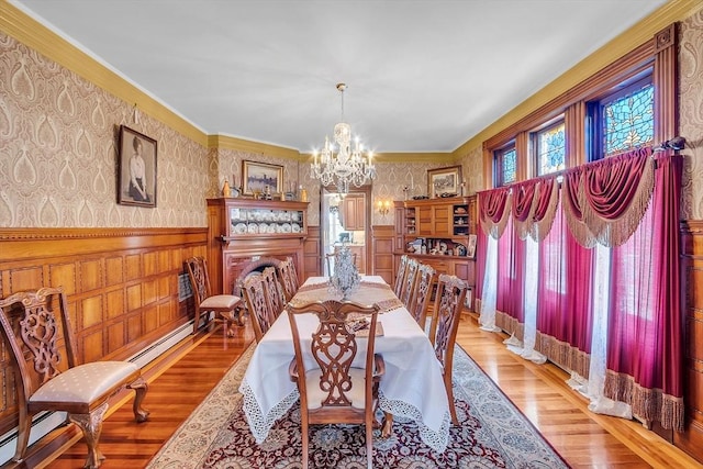 dining space with baseboard heating, crown molding, a chandelier, and light hardwood / wood-style flooring