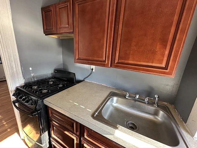 kitchen featuring wood-type flooring, sink, and black range with gas stovetop