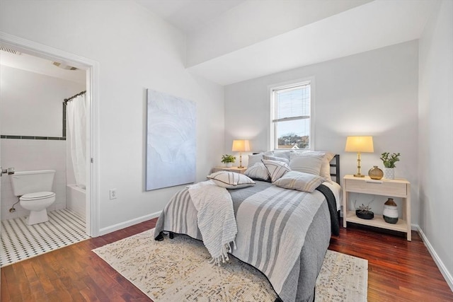 bedroom featuring ensuite bathroom, tile walls, and dark wood-type flooring