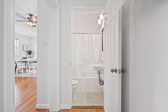 bathroom with hardwood / wood-style flooring, shower / bath combination with curtain, ceiling fan, and toilet