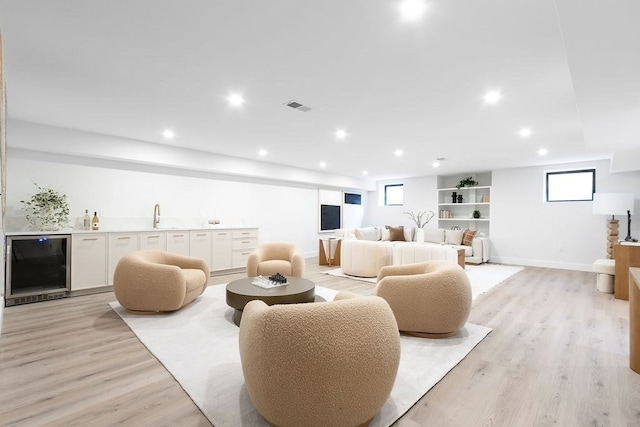 living room featuring wine cooler, sink, and light hardwood / wood-style floors