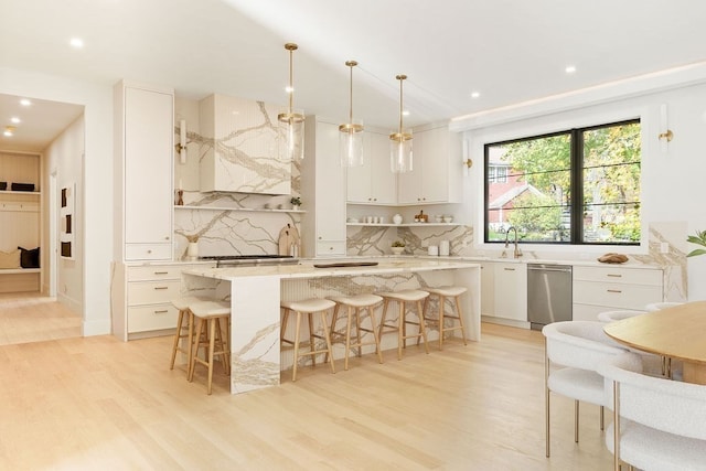 kitchen featuring a center island, white cabinets, backsplash, light wood-type flooring, and decorative light fixtures