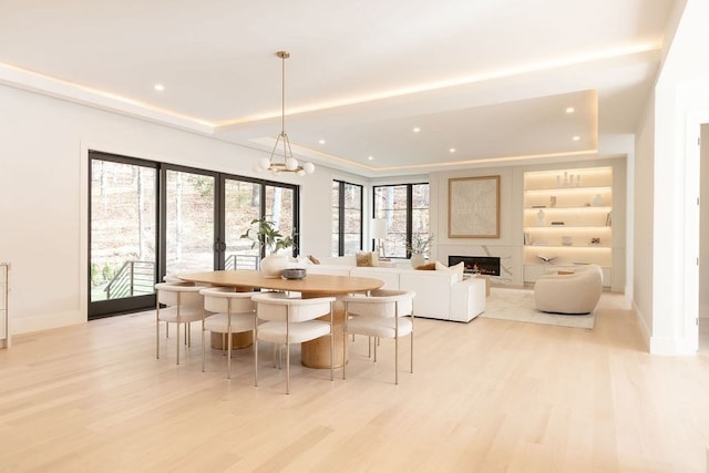 dining space with french doors, light hardwood / wood-style floors, a chandelier, and a tray ceiling