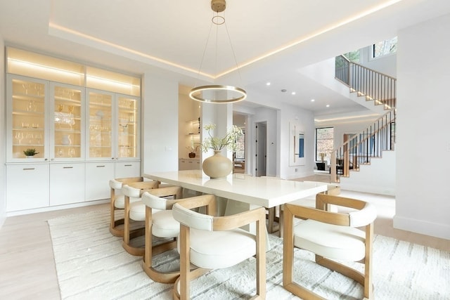 dining space featuring light hardwood / wood-style flooring and a tray ceiling