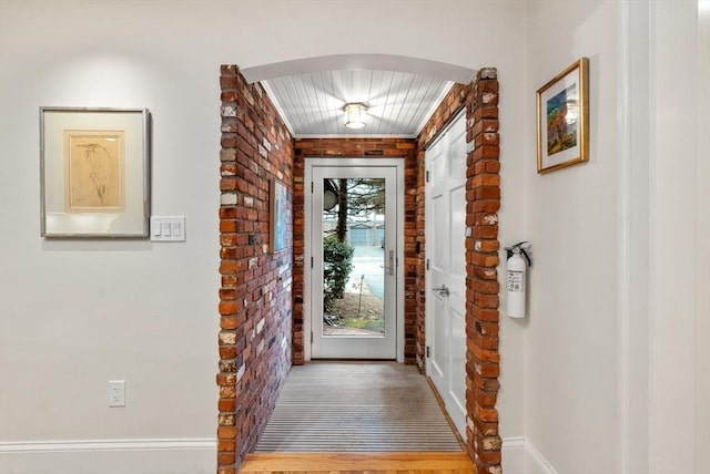 foyer featuring arched walkways and brick wall