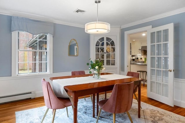 dining area featuring visible vents, wood finished floors, a baseboard heating unit, and crown molding