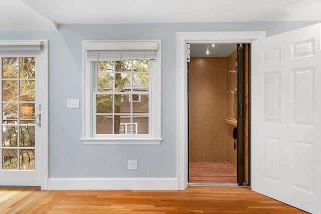 doorway featuring a wealth of natural light, baseboards, and wood finished floors