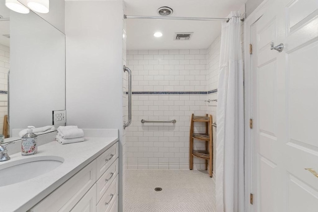 bathroom with visible vents, vanity, and a tile shower