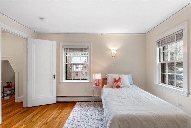 bedroom featuring a baseboard heating unit and light wood finished floors