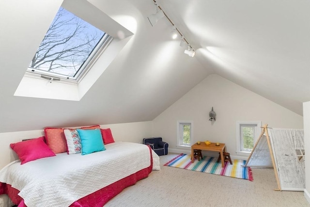 carpeted bedroom with vaulted ceiling with skylight and track lighting