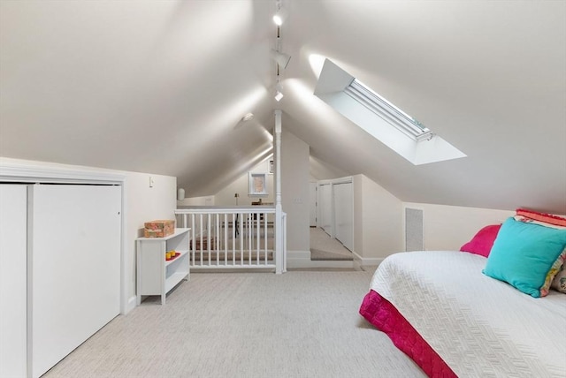 bedroom featuring lofted ceiling with skylight, rail lighting, carpet, and visible vents