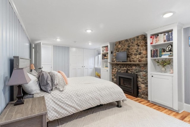 bedroom with recessed lighting, light wood-type flooring, a closet, and a fireplace