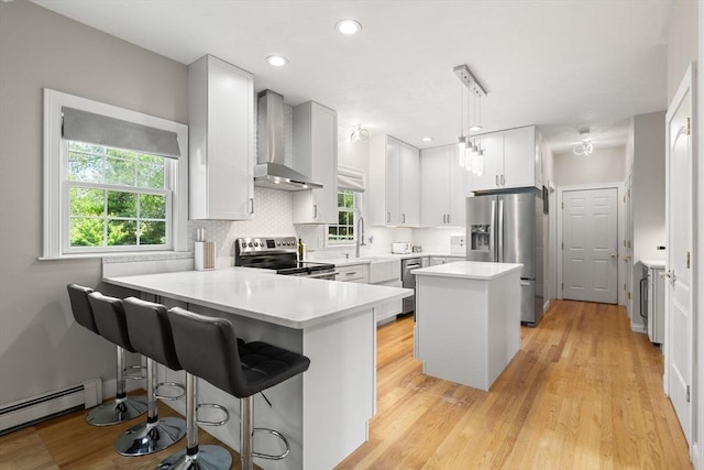 3 42nd St, Berkley, MA 02779 - kitchen featuring stainless steel appliances, wall chimney exhaust hood, a peninsula, a baseboard heating unit, and light countertops