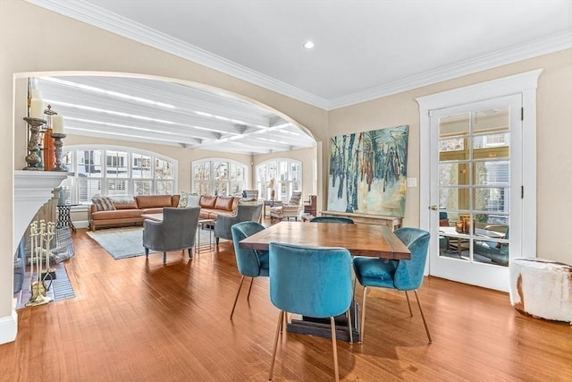 dining area with crown molding, a fireplace, wood finished floors, coffered ceiling, and beamed ceiling