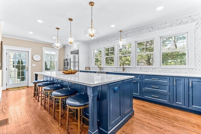 kitchen featuring pendant lighting, light countertops, a kitchen island, and blue cabinets