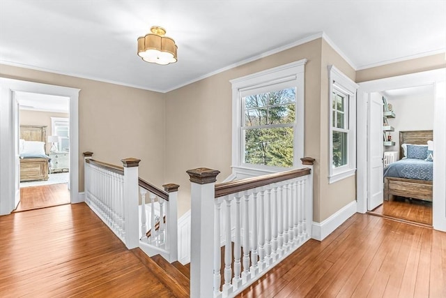 hall with baseboards, crown molding, an upstairs landing, and wood finished floors