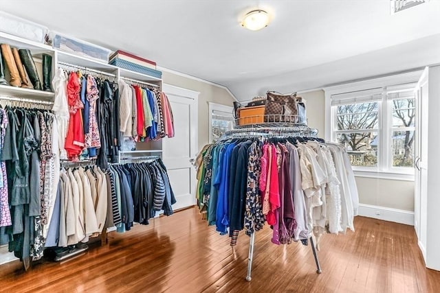 walk in closet with visible vents, vaulted ceiling, and wood finished floors