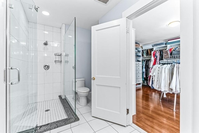 bathroom featuring toilet, visible vents, tile patterned floors, a stall shower, and a walk in closet