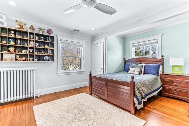 bedroom with baseboards, visible vents, radiator heating unit, ornamental molding, and wood finished floors