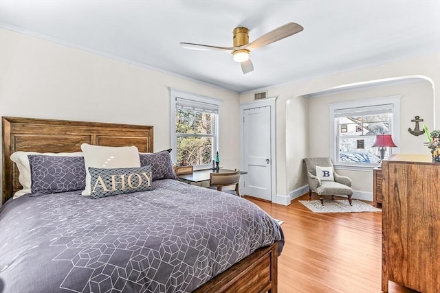 bedroom with ornamental molding, visible vents, multiple windows, and wood finished floors