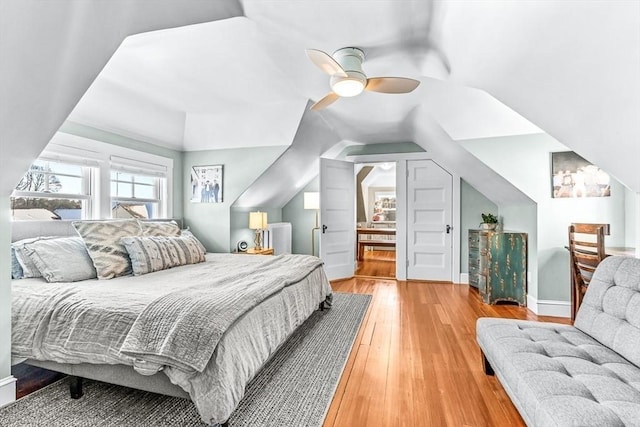 bedroom featuring a ceiling fan, vaulted ceiling, baseboards, and wood finished floors