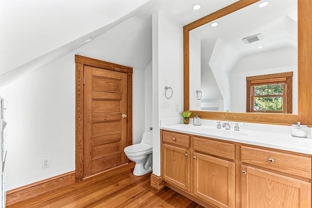 bathroom with visible vents, toilet, lofted ceiling, wood finished floors, and vanity