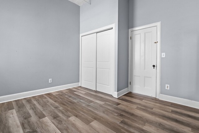 unfurnished bedroom with a towering ceiling, hardwood / wood-style flooring, and a closet