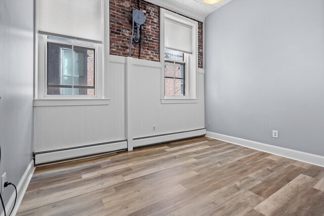 empty room with baseboard heating and light wood-type flooring