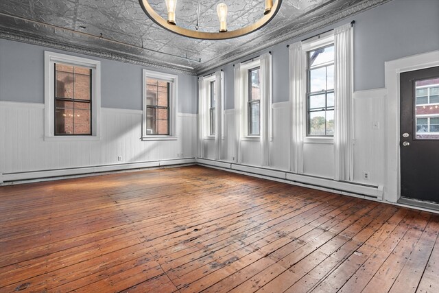 spare room featuring hardwood / wood-style flooring, a baseboard heating unit, and ornamental molding