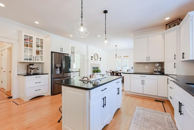 kitchen featuring white cabinetry, stainless steel fridge, and decorative light fixtures