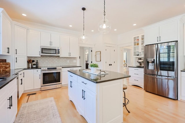 kitchen featuring tasteful backsplash, appliances with stainless steel finishes, a kitchen island, pendant lighting, and white cabinets