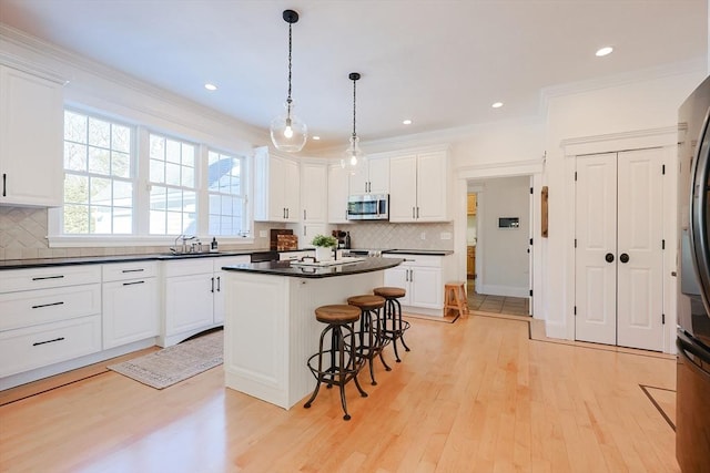 kitchen with a center island, white cabinets, a kitchen bar, and decorative light fixtures