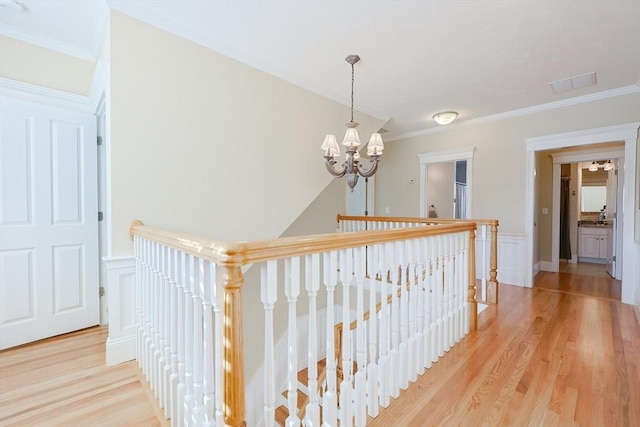 hall featuring ornamental molding, a notable chandelier, and light hardwood / wood-style floors