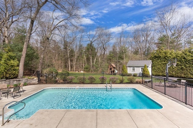 view of swimming pool with an outbuilding, a playground, and a patio