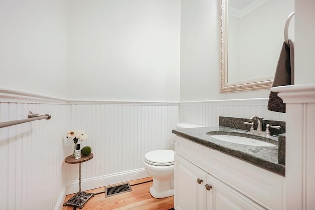 bathroom with ornamental molding, wood-type flooring, toilet, and vanity