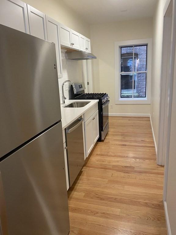 kitchen featuring white cabinets, appliances with stainless steel finishes, light hardwood / wood-style flooring, and sink